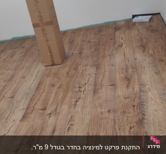 רצפת פרקט עץ עם קופסה וקרטון בחדר